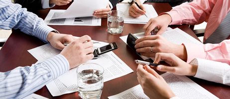 mødebord med deltagere papirer mobiler og kuglepenne.jpg